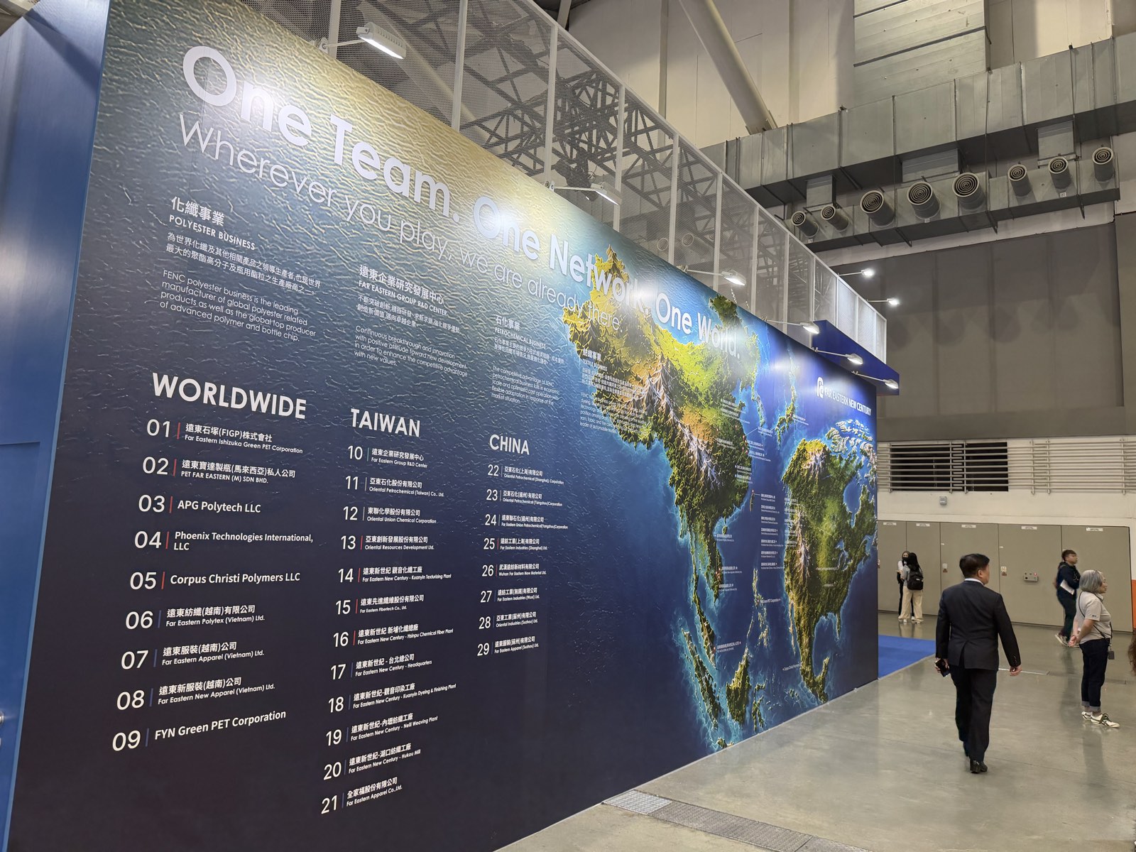Tall wall with a relief world map and the headline One Team. One Network. One World, listing FENC operations worldwide, in Taiwan and in China