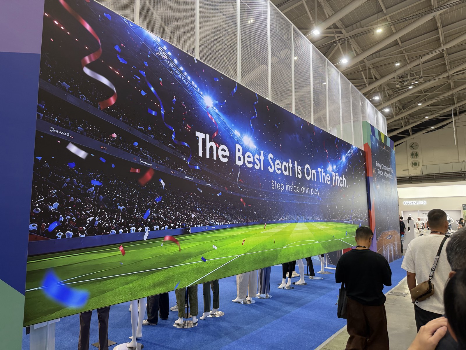 FENC booth perimeter wall at TITAS 2026: a packed stadium under lights with the headline The Best Seat Is On The Pitch. Step inside and play.