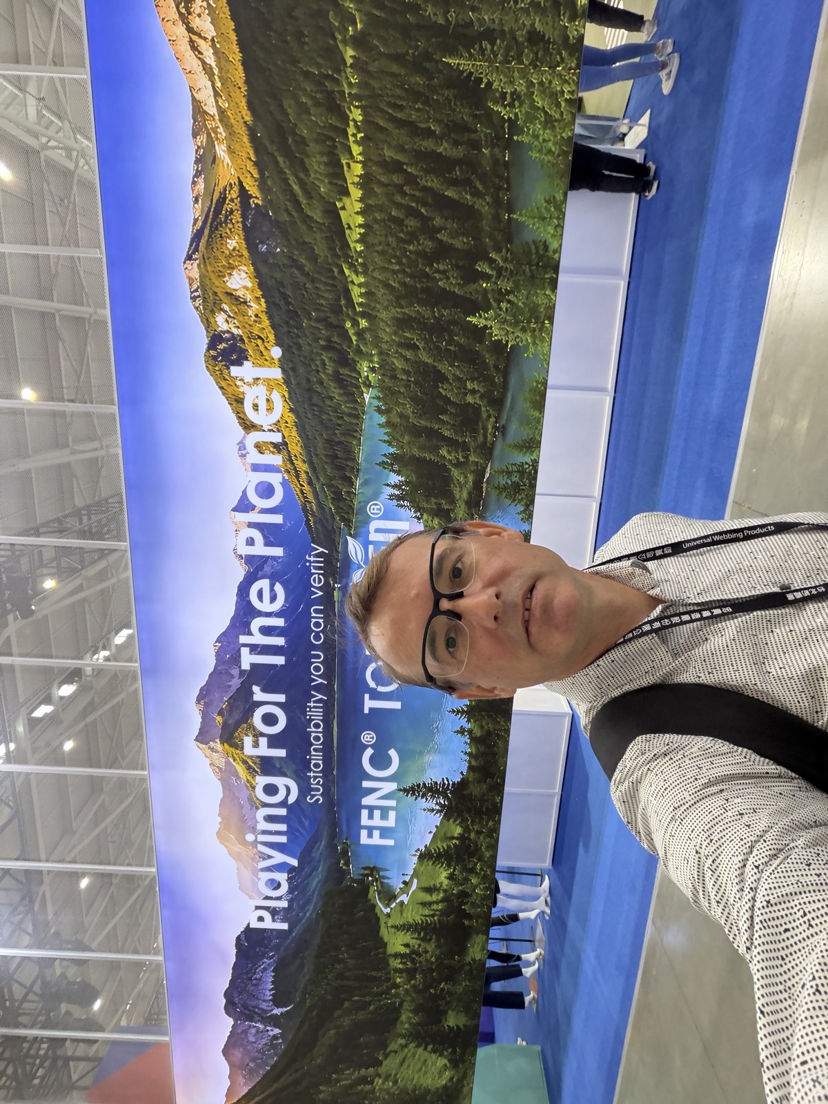 Tomasz Hasinski of Brainiak in front of the FENC TOPGREEN wall reading Playing For The Planet. Sustainability you can verify.