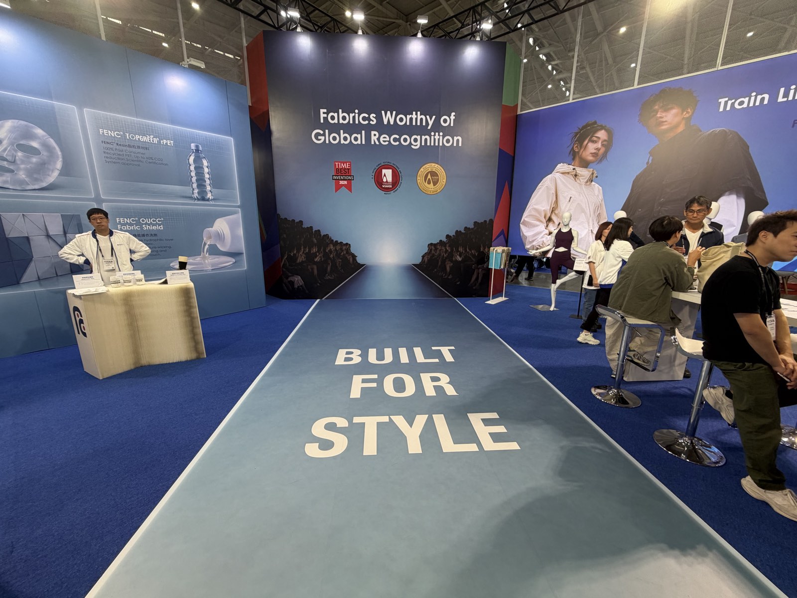 A runway-style floor reading BUILT FOR STYLE leading to a wall headed Fabrics Worthy of Global Recognition with three award badges